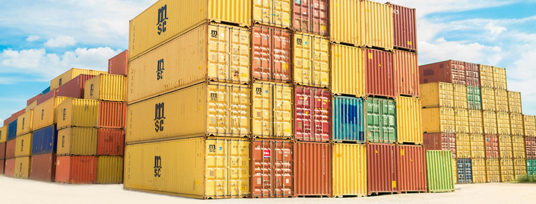 Dozens of stacked cargo containers in front of the blue sky