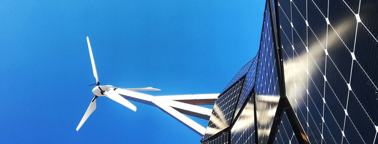 Solar cells and a wind turbine against a blue sky