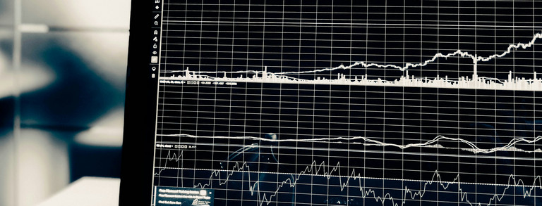 Computer screen showing multiple graphs with glass office door in background