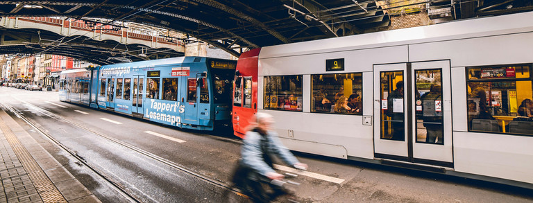 Streetcar driving under a bridge while a cyclist rides along